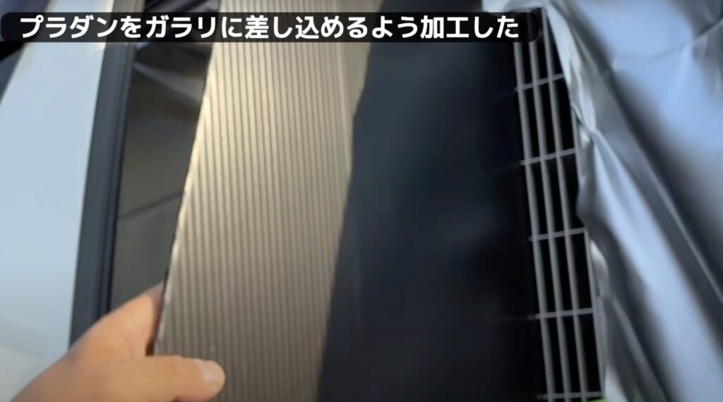 窓エアコンの給排気の効率を上げるために間にプラダンを差し込んでいるシーン