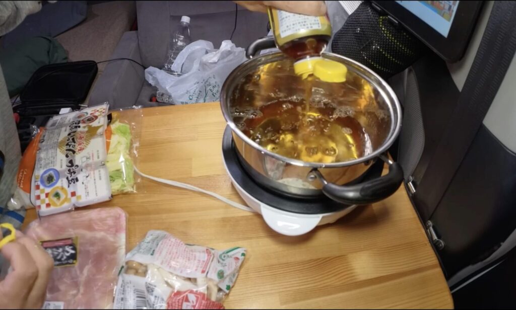 車内でラウンドホットプレートとダイソーの鍋を使って寄せ鍋を調理している様子