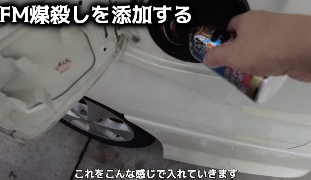 アルファードの給油口からFM煤殺しを注入している様子。